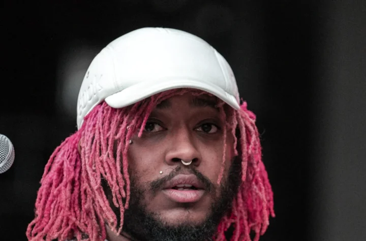 Thundercat holding his bass on stage in a white cap