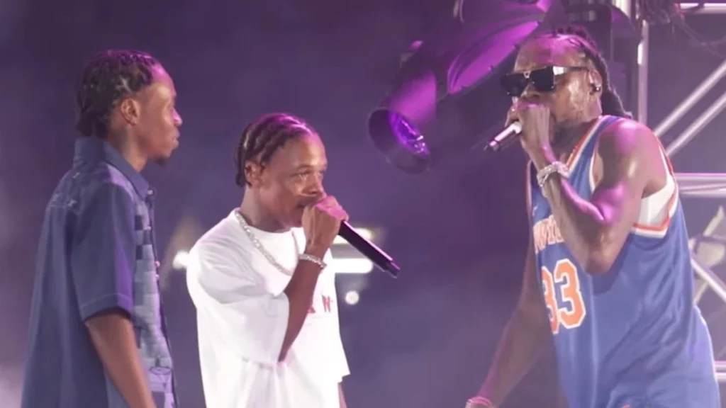 Vybz Kartel performing on stage with his sons under purple lights