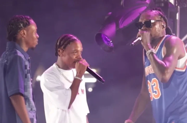 Vybz Kartel performing on stage with his sons under purple lights