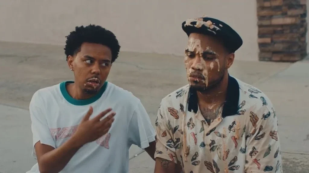 Cordae and Anderson .Paak sit on a kerb in a still from the A Good Day video