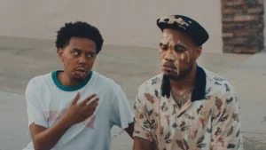 Cordae and Anderson .Paak sit on a kerb in a still from the A Good Day video