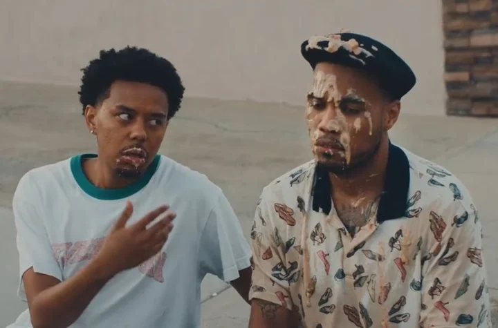 Cordae and Anderson .Paak sit on a kerb in a still from the A Good Day video